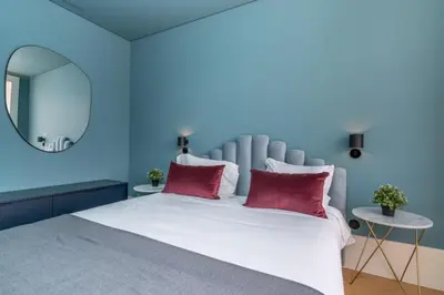 a blue bedroom with a large bed with red pillows at Infante Apartment by Amber Star Rent in Porto
