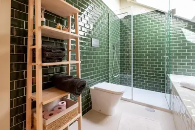a bathroom with green tiled walls and a toilet at Oporto INNside House in Porto