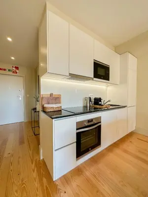 a kitchen with white cabinets and a stove top oven at My homey at Flores in Porto