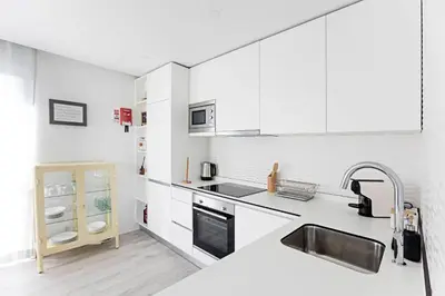 a white kitchen with white cabinets and a sink at Stylish Flat W/ Gym & Parking by LovelyStay in Porto