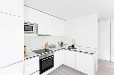 a white kitchen with white cabinets and a sink at Stylish Flat W/ Gym & Parking by LovelyStay in Porto