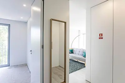 a hallway with a mirror and a couch in a room at Stylish Flat W/ Gym & Parking by LovelyStay in Porto