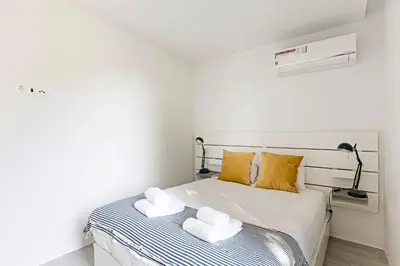 a white bedroom with a bed with towels on it at Stylish Flat W/ Gym & Parking by LovelyStay in Porto