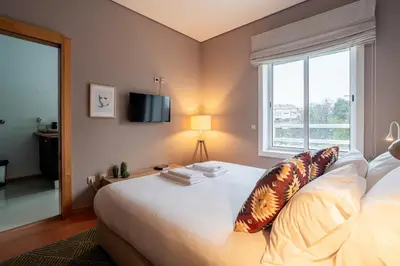 a bedroom with a large white bed with a window at Taupe Studio perto do Metro - Cedofeita, Porto in Porto