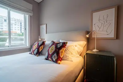 a bedroom with a bed with pillows and a window at Taupe Studio perto do Metro - Cedofeita, Porto in Porto