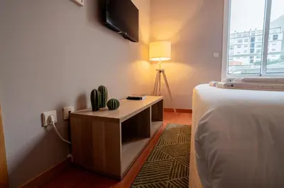 a bedroom with a bed and a desk with a tv at Taupe Studio perto do Metro - Cedofeita, Porto in Porto