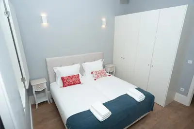 a bedroom with a white bed with two red pillows at Porto XL in Porto