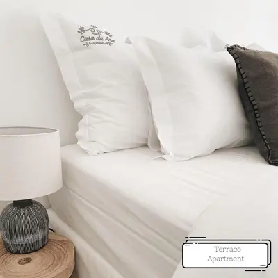 a bed with white sheets and pillows next to a lamp at Manuel Apartment - Porto Velho Apt in Porto