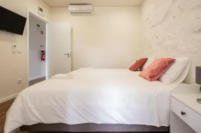 a bedroom with a white bed with red pillows at Entire House with 4 Master Suites, Hot Tub & Backyard - Central Location in Vila Nova de Gaia