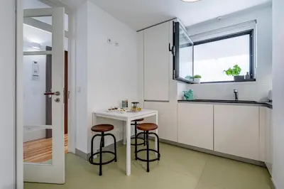 a white kitchen with two stools and a small table at Art Douro Historic Distillery in Vila Nova de Gaia