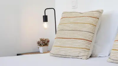 a pillow sitting on a bed next to a lamp at OPOrto Downtown Studio by LovelyStay in Porto