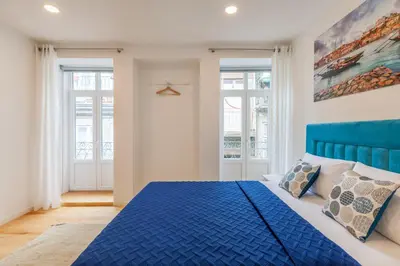 a bedroom with a blue bed and two windows at Villa Apartments & Suites in Porto