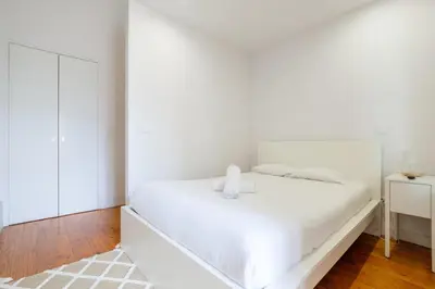 a white bedroom with a white bed and a mirror at GuestReady - Bolhão Market Place in Porto