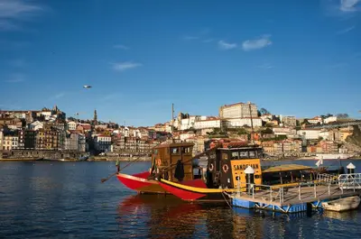 two boats are docked in the water near a city at WLoft in Vila Nova de Gaia