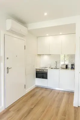 an empty kitchen with white cabinets and a wooden floor at Guest H4U - Porto Bonfim Heroismo in Porto