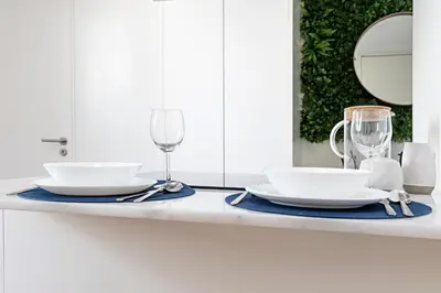 a table with two white plates and wine glasses at Cozy House w/ AC near metro by LovelyStay in Porto