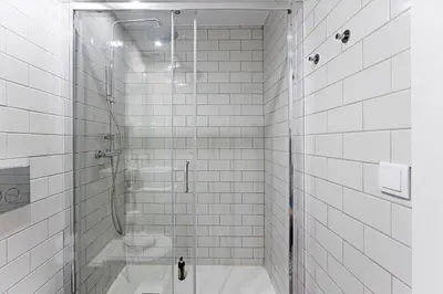 a white tiled bathroom with a glass shower stall at Lapa Flat in City Center by LovelyStay in Porto