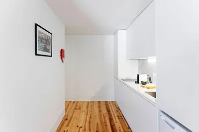 a kitchen with white walls and a wooden floor at Lapa Flat in City Center by LovelyStay in Porto