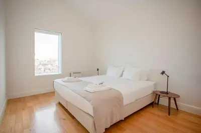a white bedroom with a white bed and a window at Liiiving in Gaia - Douro Dream View in Vila Nova de Gaia