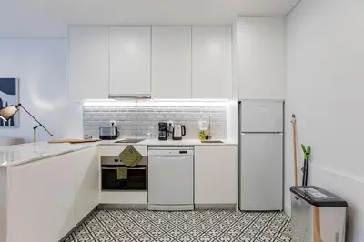 a white kitchen with white cabinets and appliances at Downtown Wonder Flat w/ AC by LovelyStay in Porto