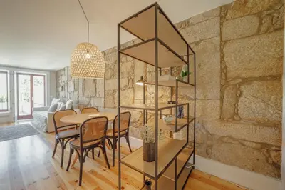 a dining room and living room with a stone wall at Boavista Premium Apartments by Vacationy in Porto