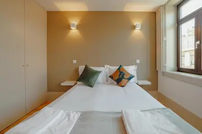 a bedroom with a large white bed and a window at Legacy Oporto Premium Apartments by Vacationy in Porto