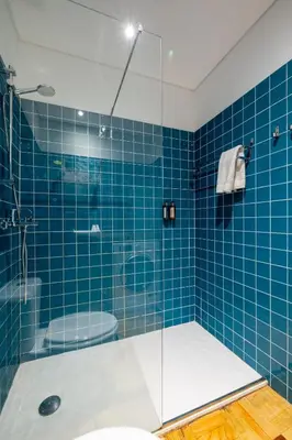 a blue tiled bathroom with a shower and a toilet at Casa do Ofício Galerista in Porto
