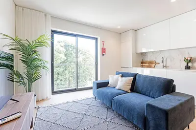 a blue couch in a living room with a large window at NEW Cozy and Modern Apartment in the heart of Porto in Porto