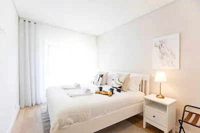 a white bedroom with a white bed and a window at Paraíso 1H w/ AC by LovelyStay in Porto
