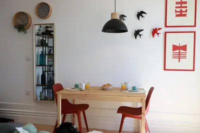 a dining room table with two red chairs and a light fixture at Cedofeita Charming Flat in Porto
