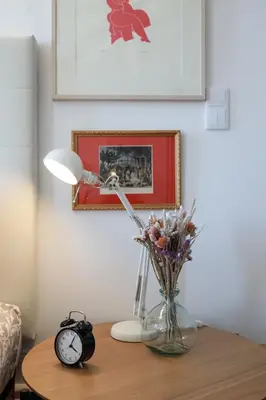a table with a vase of flowers and a clock at Cedofeita Charming Flat in Porto