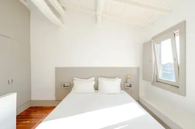 a white bedroom with a white bed and a window at VIVA Old Street Homes in Porto