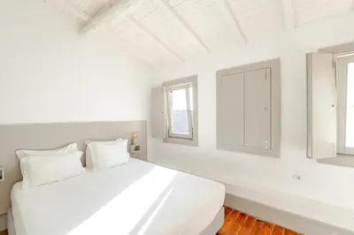 a white bedroom with a large bed and two windows at VIVA Old Street Homes in Porto