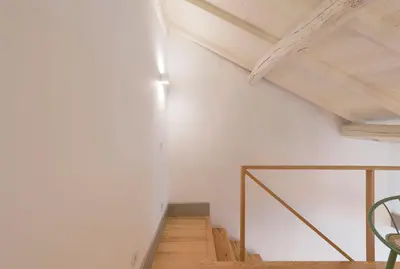 a room with a white wall and a wooden staircase at VIVA Old Street Homes in Porto