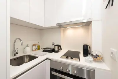 a small kitchen with white cabinets and a sink at Santo António Oporto House in Porto