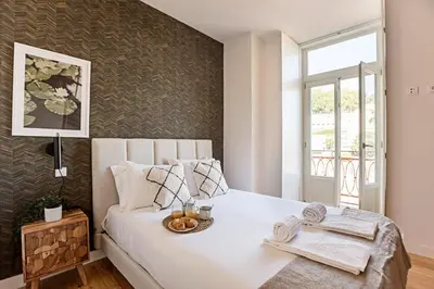 a bedroom with a white bed and a window at Stunning Duplex Near River by LovelyStay in Porto