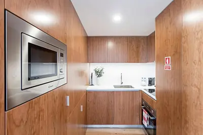 a kitchen with wooden cabinets and a flat screen tv at Stunning Duplex Near River by LovelyStay in Porto