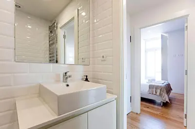 a white bathroom with a sink and a mirror at Stunning Duplex Near River by LovelyStay in Porto