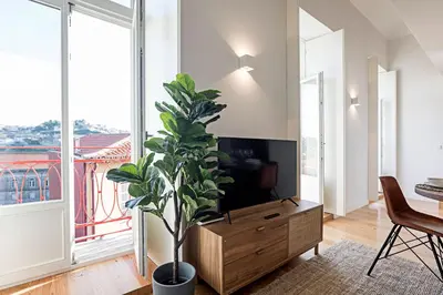 a living room with a tv and a potted plant at Stunning Duplex Near River by LovelyStay in Porto