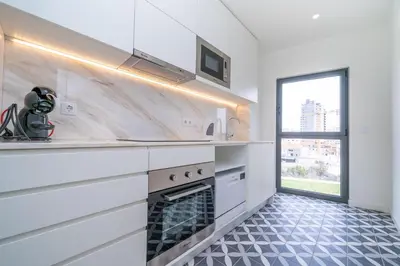 a white kitchen with a stove and a window at Trindade Duplex by Amber Star Rent in Porto