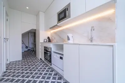 a kitchen with white cabinets and a black and white tile floor at Trindade Duplex by Amber Star Rent in Porto