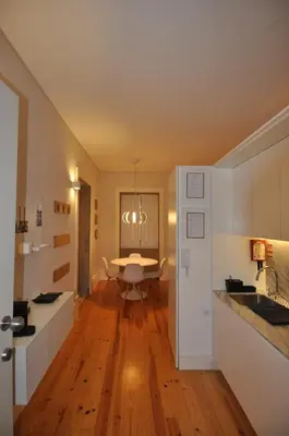 a kitchen with white cabinets and a wooden floor at Santo António Elegant Flat in Porto