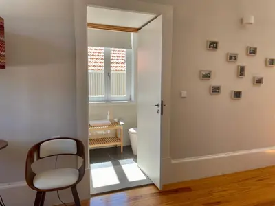 a bathroom with a toilet and a chair in a room at Santo António Elegant Flat in Porto