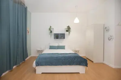 a white bedroom with a bed and blue curtains at Bonsai Apartment III in Porto