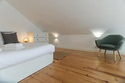 a bedroom with a white bed and a chair at Loft Martires da Liberdade by Porto City Hosts in Porto