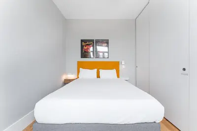 a bedroom with a large white bed with an orange headboard at GuestReady - Colorful Apt near Agosto Station in Porto