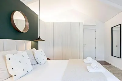 a bedroom with a large white bed with a mirror at Wonderful 2BR Duplex Near River by LovelyStay in Porto
