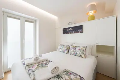 a white bedroom with a bed and a window at 31 de Janeiro Oporto House in Porto