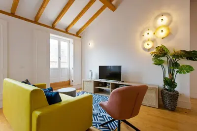 a living room with yellow chairs and a tv at BOUTIQUE Rentals-THE ALMA Apt w/ balcony in Porto