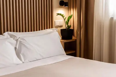 a bed with white sheets and a plant on a table at room Select Porto in Porto